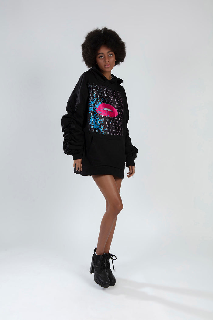 Model in black Lips Graphic oversized hoodie dress with ruched sleeves, streetwear aesthetic for Gen Z fashion.