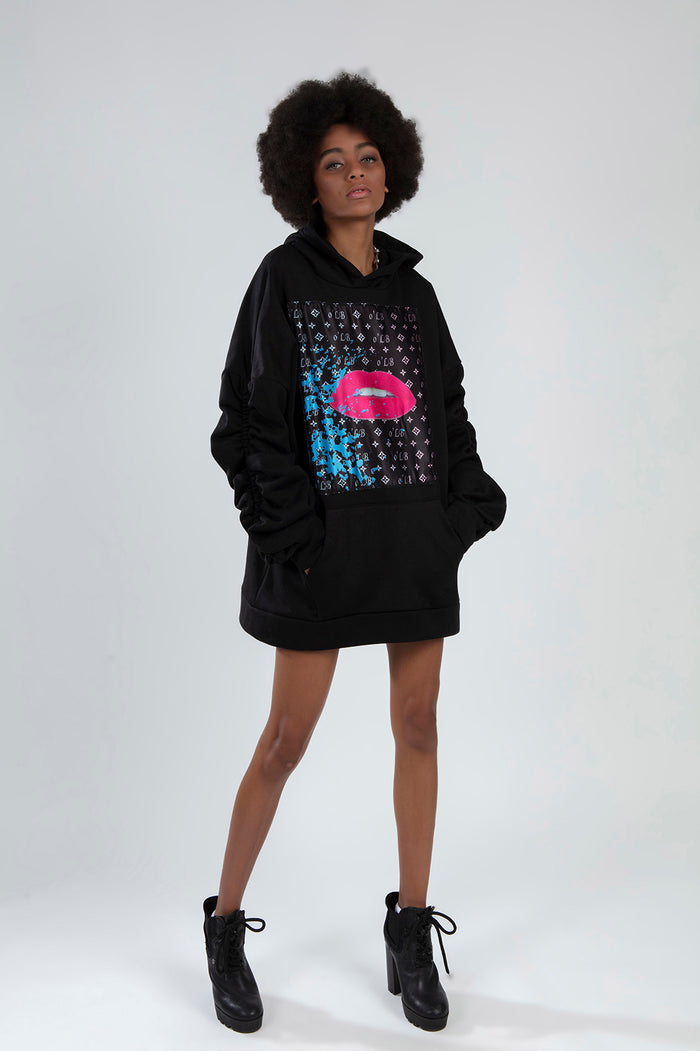 Model in an oversized black hoodie with a pink lips graphic print, ruched sleeves, and front pocket.