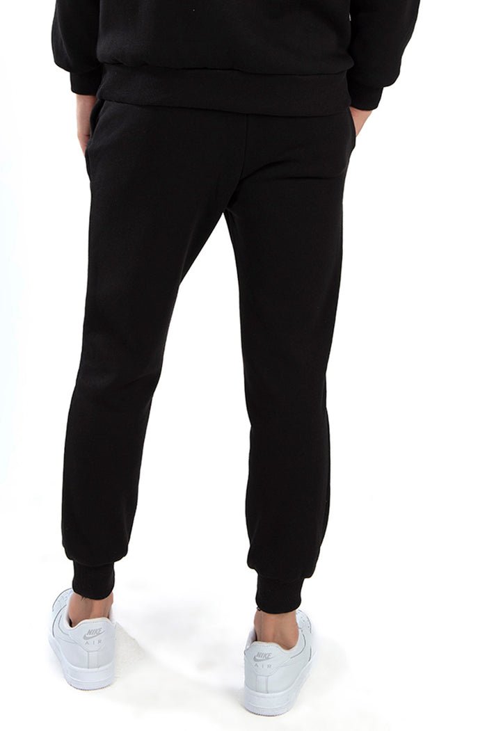 Back view of a person wearing Carbon Jeans black streetwear joggers and Love Hoodie with white sneakers.