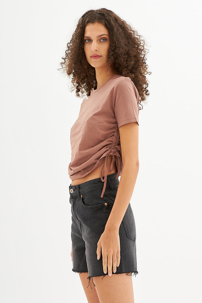 Model in Lucy Side String Brown Crop Top with ruched drawstring detail and black denim shorts, streetwear vibe.