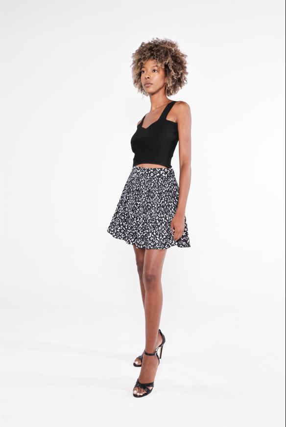 Model wearing the black Luna ribbed cropped tank top paired with a black and white patterned mini skirt and heels.