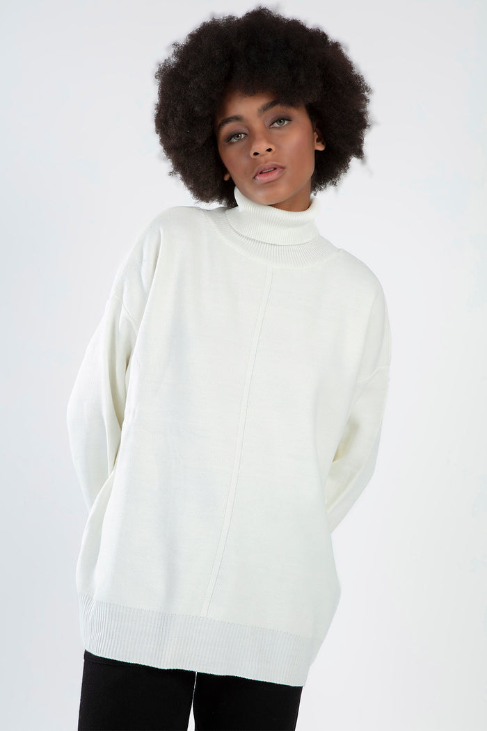 Model wears the Mabel Cream Knit Sweater, a white oversized turtleneck with drop shoulders and ribbed cuffs.