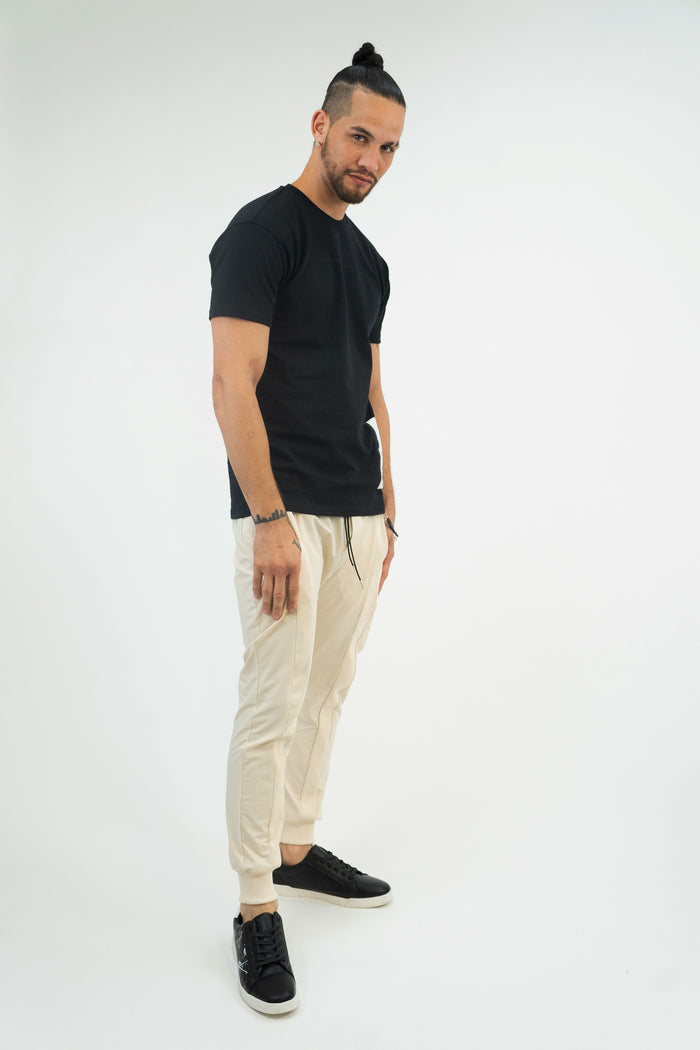 Model wearing MAC cream drawstring jogger pants in a slim-fit streetwear style with cuffed ankles.
