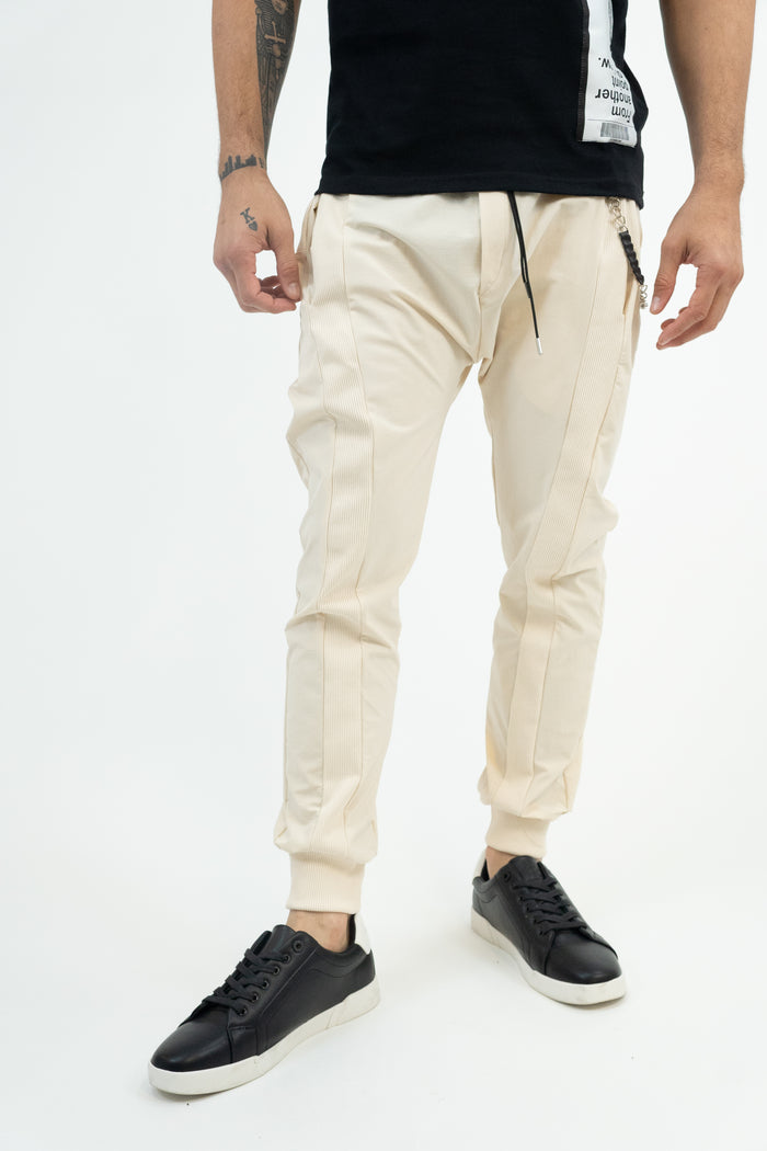 Model wearing MAC cream streetwear pants with ribbed side panels, drawstring waist, and cuffed ankles.