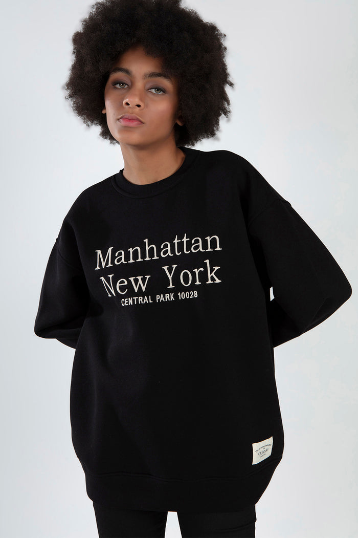 Model wearing Manhattan Top, a black oversized sweatshirt with white New York Central Park embroidery.