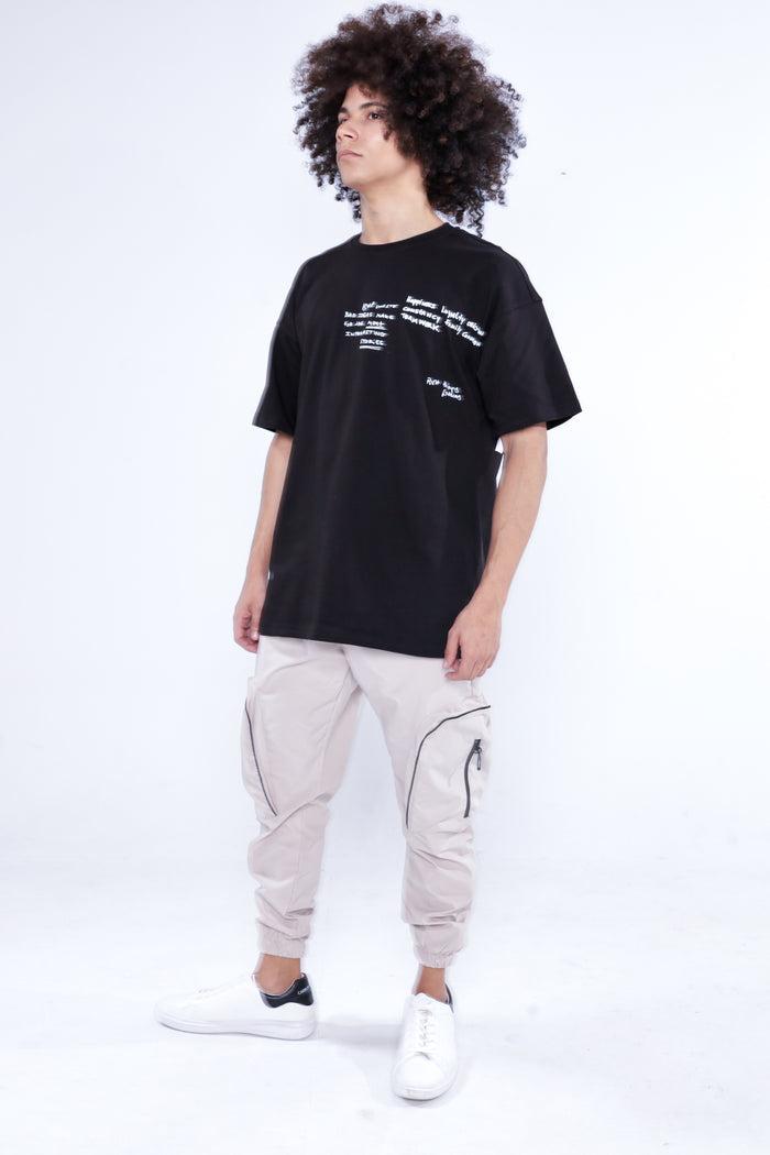 Model wearing Melvin stone cargo pants with utility zip pockets and a black streetwear t-shirt.