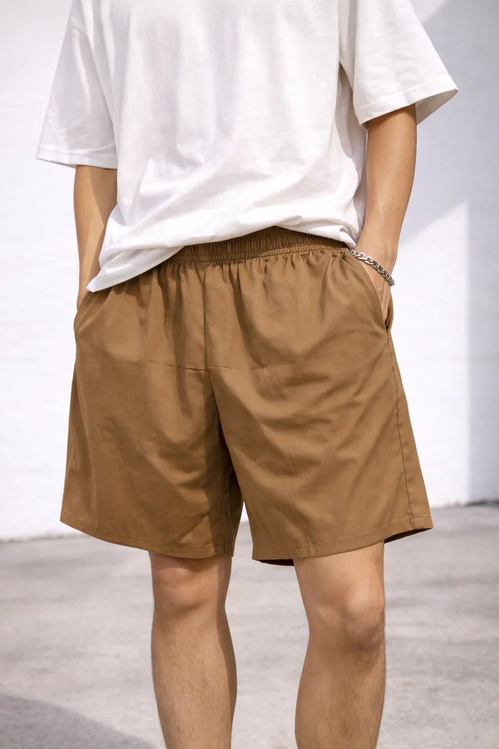 Man wearing casual brown shorts and white t-shirt outdoors