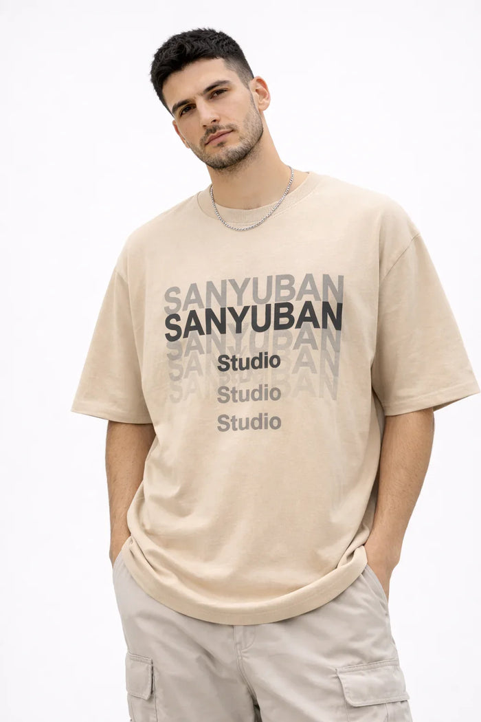 Man wearing a beige graphic t-shirt with SANYUBAN Studio text and cargo shorts