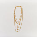 Golden Glow Minimalist layered necklace featuring a gold curb chain, starfish charm, and gemstone on a white background.