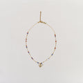 Golden initial E pendant necklace with red, white, and blue beads on a minimalist chain with a lobster clasp.