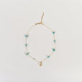 Dainty Golden Glow minimalist chain necklace with turquoise stone beads and a gold pendant on a white background.