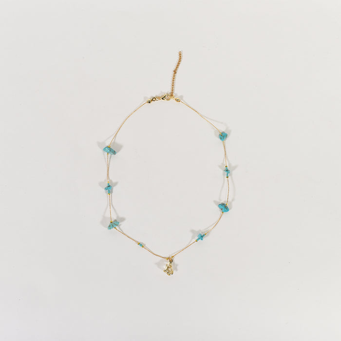 Dainty Golden Glow minimalist chain necklace with turquoise stone beads and a gold pendant on a white background.