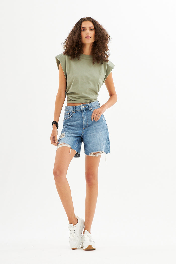 Model in a Gravity Grey padded shoulder muscle tee and distressed denim shorts, showing the structured streetwear fit.