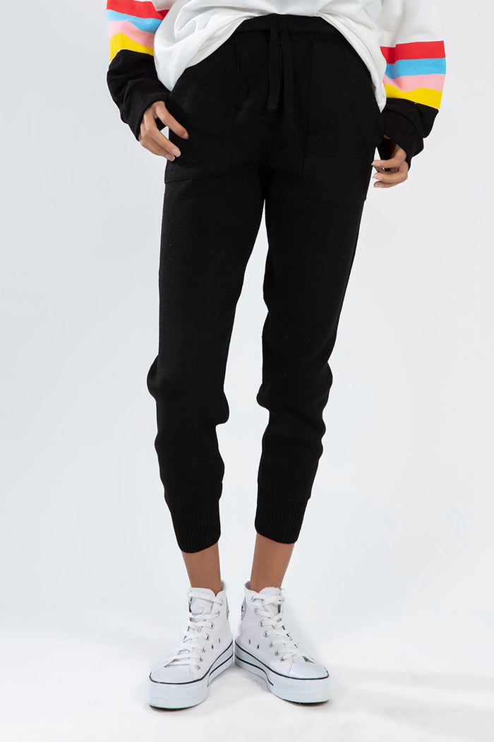 Model wearing Paris Black Knit Jogger Pants with drawstring waist and ribbed cuffs, styled with white high-top sneakers.