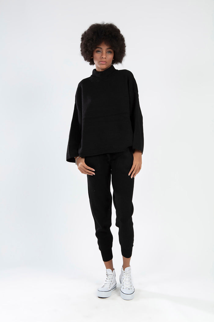 Model wearing a Paris Top Set in black, featuring a long-sleeve knit turtleneck and matching joggers with white sneakers.