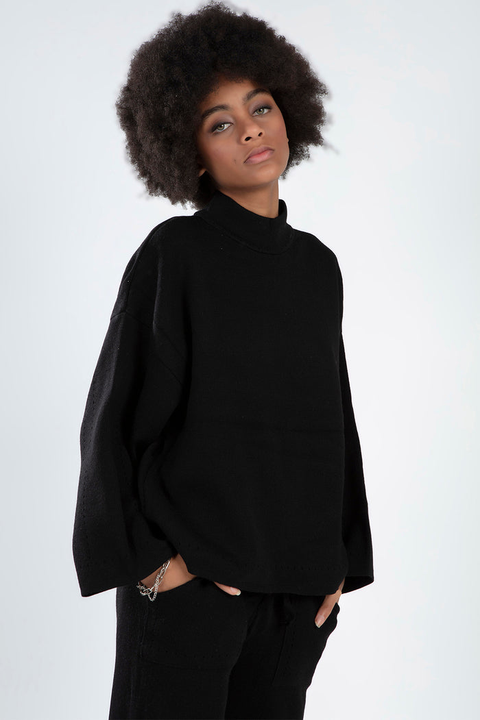 Model in the black Paris Top Set featuring a mock neck knit sweater and matching pants in a trendy streetwear co-ord style.