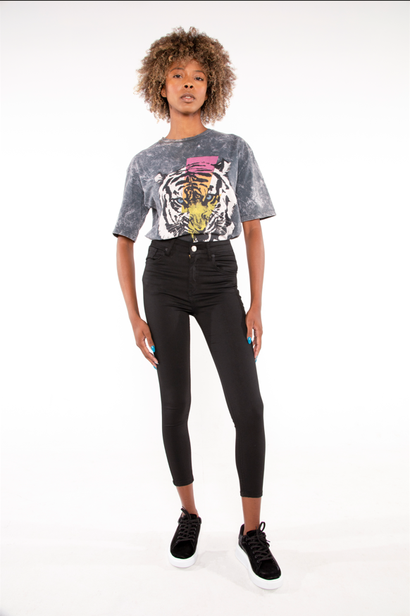 Model in an oversized grey acid wash tiger graphic tee and black high-waisted skinny jeans.