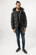 Men's Philip Puffer Coat in black with faux-fur trim hood, quilted texture, and utility pockets on a streetwear model.