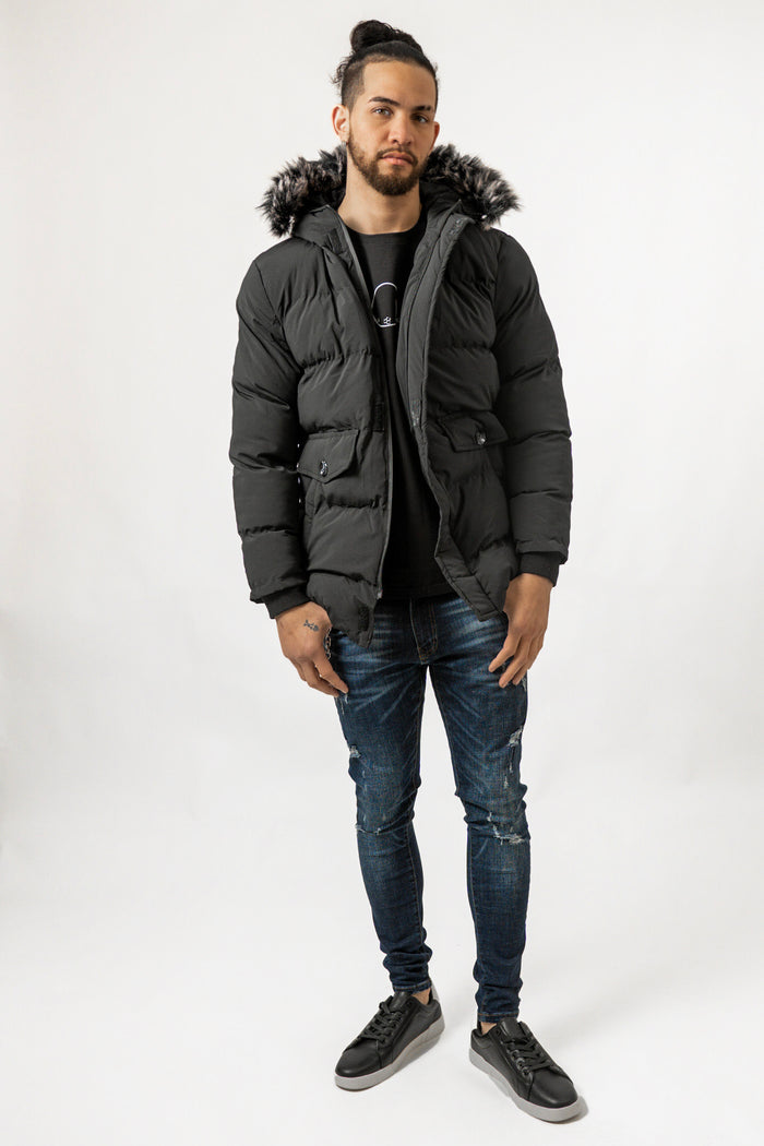 Men's Philip Puffer Coat in black with faux-fur trim hood, quilted texture, and utility pockets on a streetwear model.