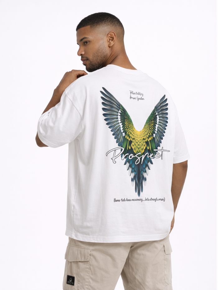 A man wearing a white oversized t-shirt featuring a colorful bird wing graphic on the back.