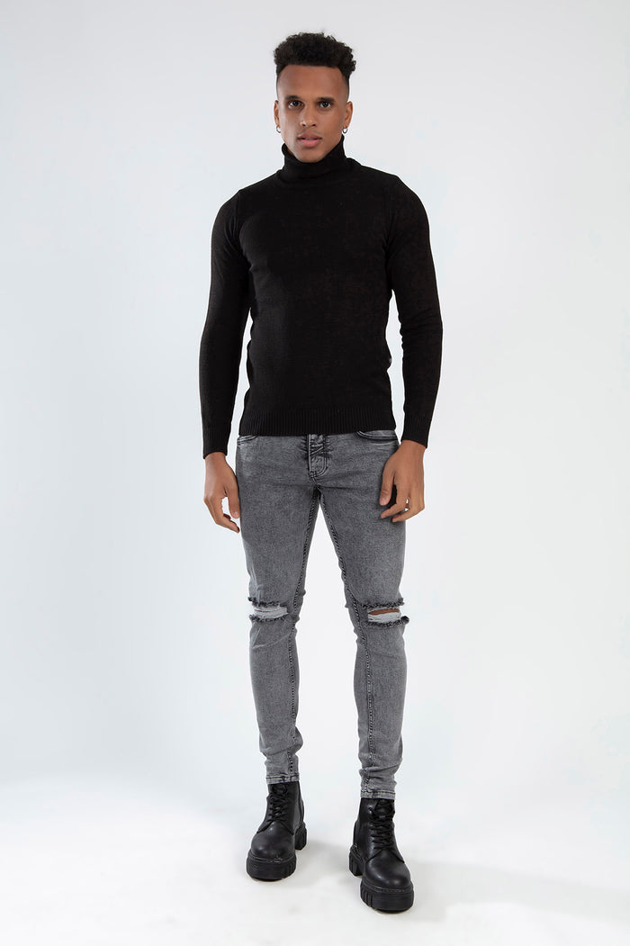 RAFAEL Super Skinny Fit Grey Jeans in Carbon wash with distressed knees on a model in a black turtleneck and boots.