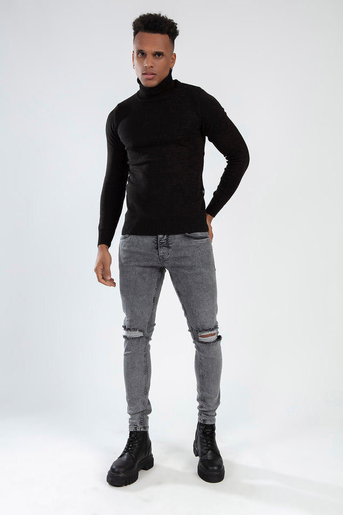 Model in RAFAEL super skinny fit grey jeans with knee rips and carbon wash, styled with a black turtleneck and boots.