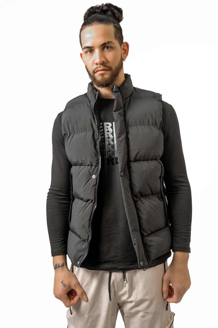 Man wearing the Randy black quilted puffer vest over a long-sleeve streetwear shirt against a white studio background.