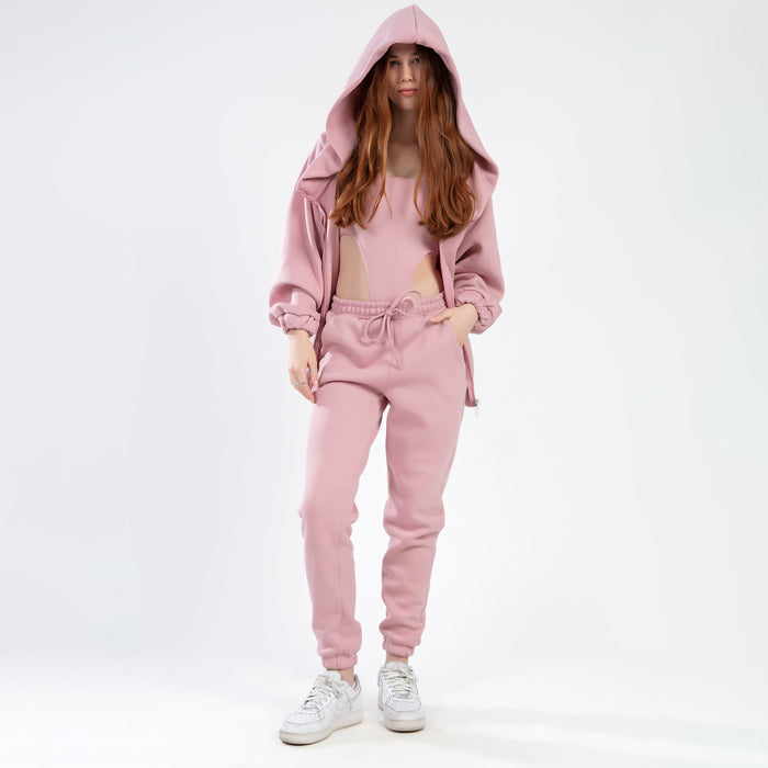 Model wears the Remi Bodysuit Set in salmon, featuring a cut-out bodysuit, matching drawstring joggers, and oversized hoodie.