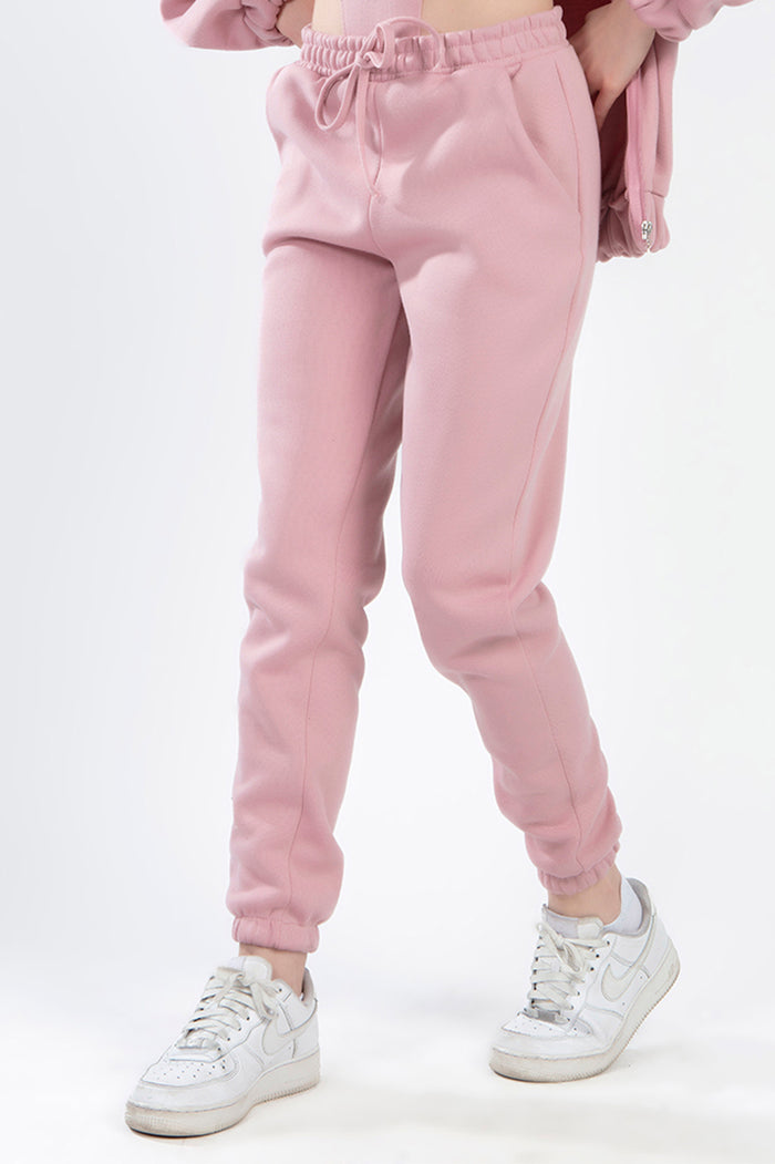 Close-up of salmon pink high-waisted joggers from the Remi two-piece set, featuring a drawstring waist and elastic cuffs.
