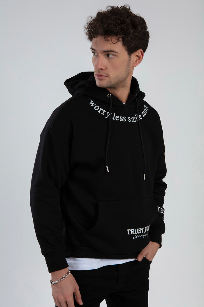 Men’s black graphic hoodie with 'Worry less smile more' text, oversized streetwear fit, front pocket, and hood.