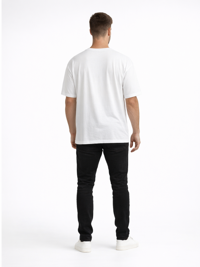 A person wearing a white t-shirt and black jeans stands with their back to the camera on a plain background.