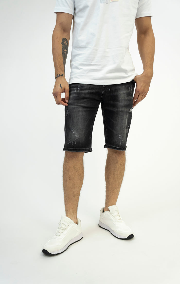 Samuel black washed denim shorts by Carbon Jeans with distressing and slim fit, shown on a model with white sneakers.