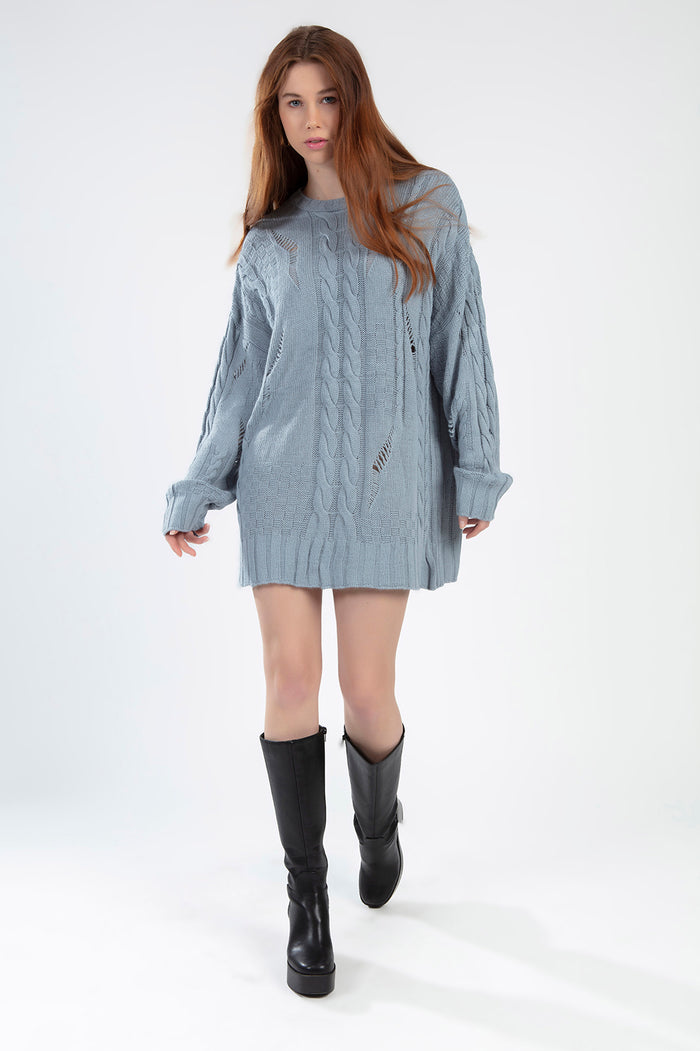 Model wearing the Saylor Sweater, a light blue oversized distressed cable knit pullover on a white background.