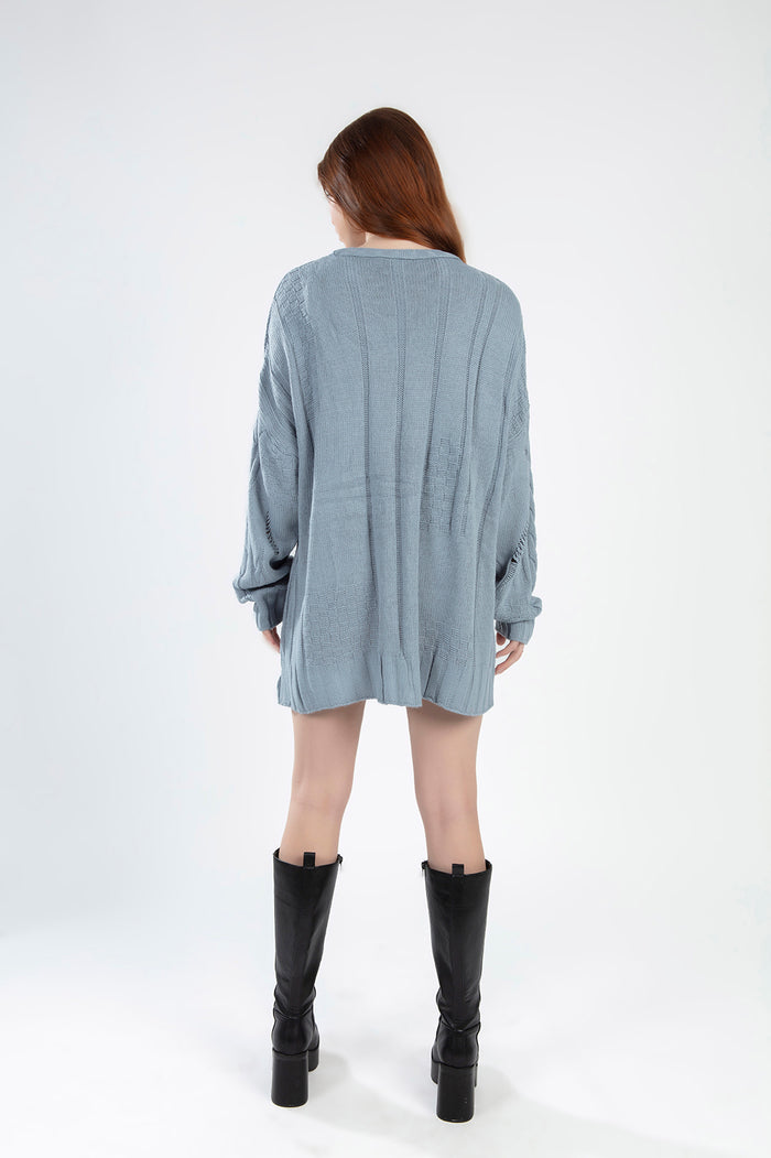 Rear view of the Saylor blue oversized cable knit sweater featuring distressed detailing and a relaxed tunic fit.
