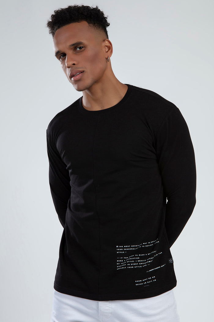 Model in black Show Must Go On long-sleeve graphic tee by Carbon Jeans with white text and vertical seam detail.
