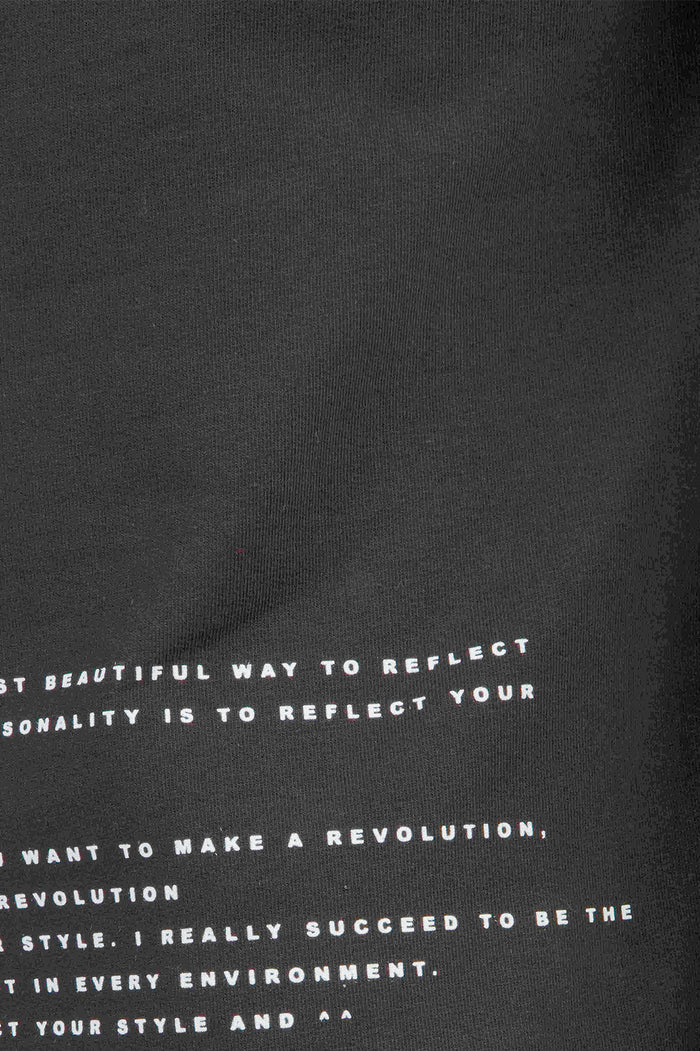Close-up of the Show Must Go On black graphic t-shirt featuring white sans-serif motivational text in streetwear style.