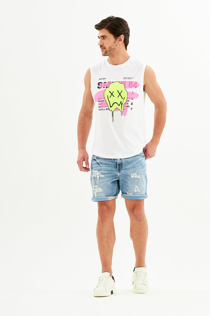 Model wearing a white Smile Graphic Tank Top with neon melting smiley print and distressed blue denim shorts.
