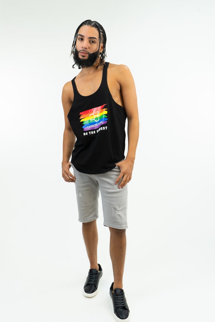 Man in black Stringer Pride Tank Top with rainbow logo and gray shorts, showing muscle-fit bodybuilding gym wear.