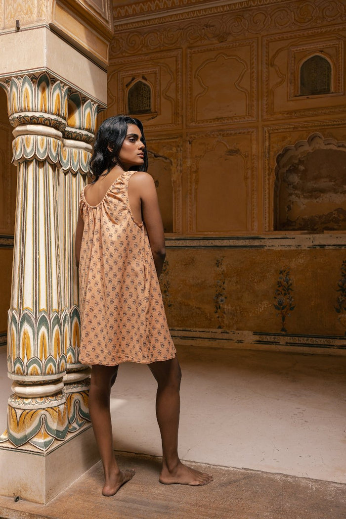 Sundress Mini Peach — studio side profile, sleeveless mini dress with short hemline showing legs, flowing tie-gather neckline, hand block print peach cotton, artisan India | Daughters of India