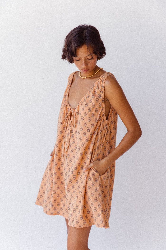 Sundress Mini Peach — close-up neckline tie detail, adjustable gathered bow at neckline, peach floral block print cotton fabric detail, handcrafted artisan India | Daughters of India
