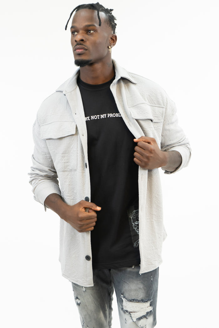 Man wearing Carbon Jeans textured knit top in light grey over a black graphic tee with urban streetwear style.