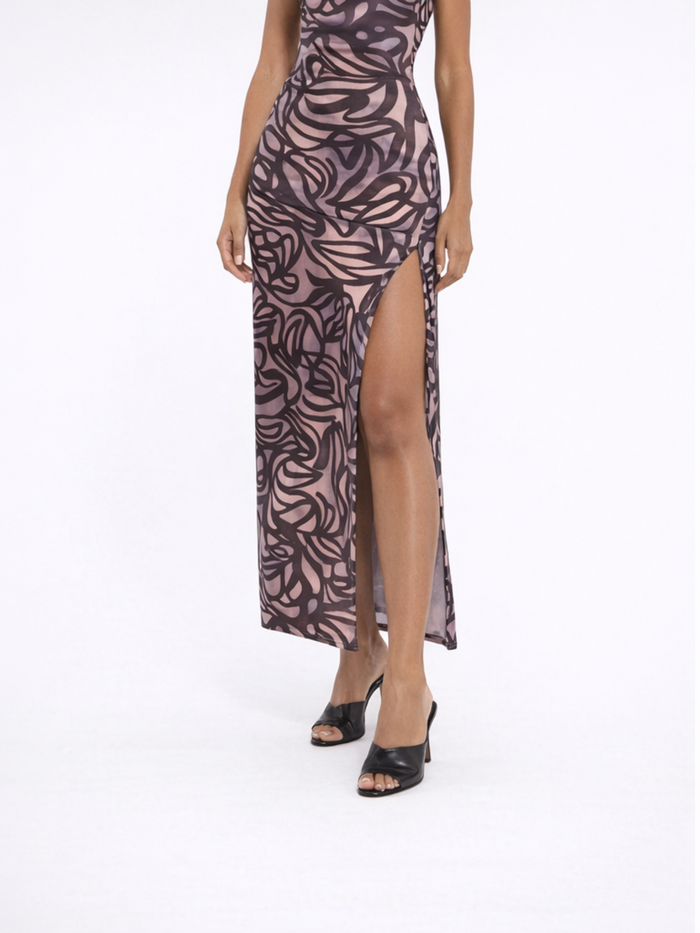 A model wearing a form-fitting dress with a floral pattern and a thigh-high slit, paired with black heels.