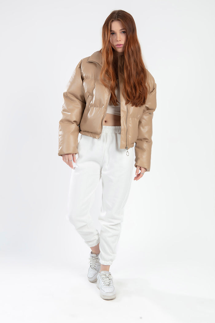 Model wearing Thea beige vegan leather puffer coat with white joggers and sneakers, street style fashion.