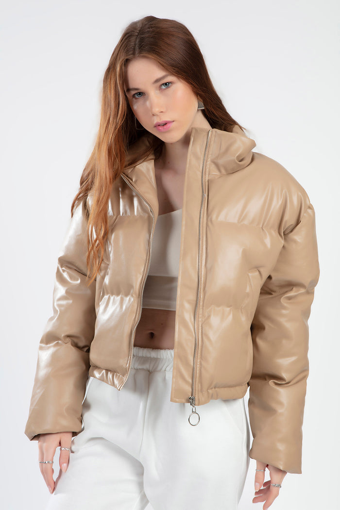 Model wearing the Thea beige faux leather puffer coat with a high collar and ring-pull zipper in a cropped fit.