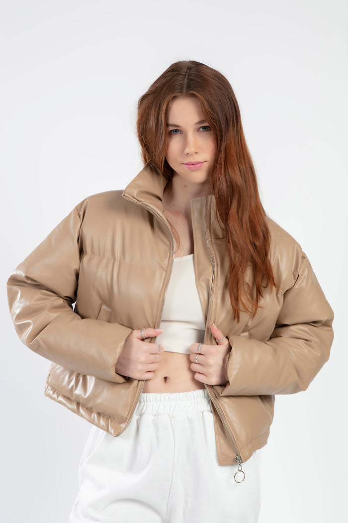 Model wearing the Thea beige vegan leather puffer coat, a cropped outerwear style for women by Carbon.