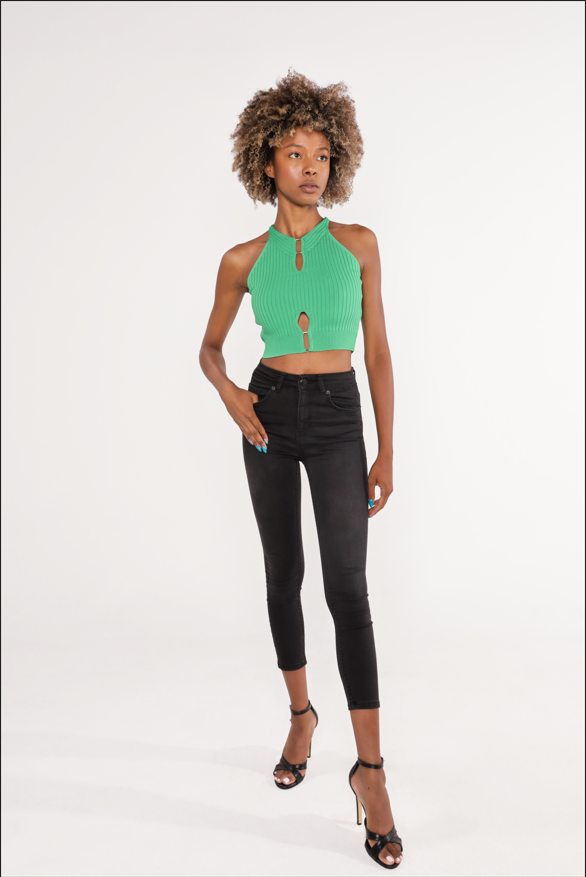 Model wearing Tori Top, a green ribbed knit halter top with keyhole cutouts and metal hardware detail.