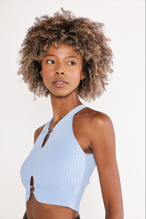 Model wearing the Tori Top, a light blue ribbed knit halter top with hardware details and a cropped fit.