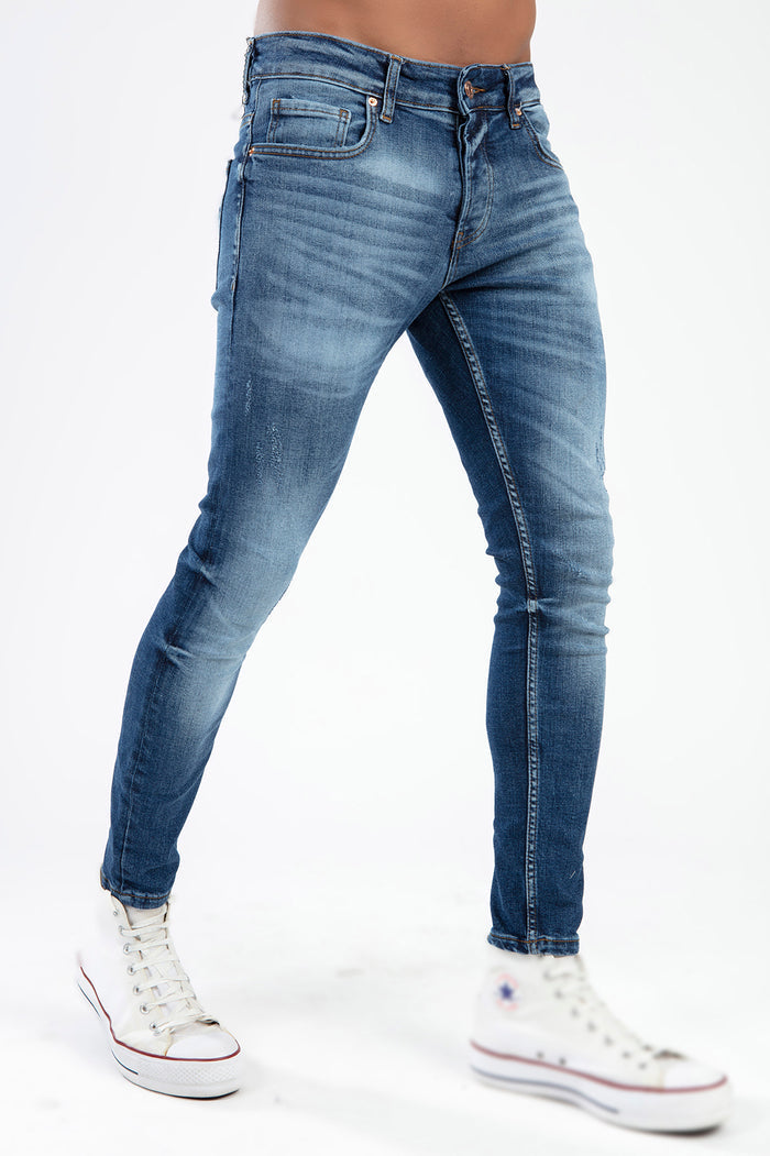 Men's Tristan super skinny jeans in a blue wash with vintage fading, distressing, and whiskering on the thighs.