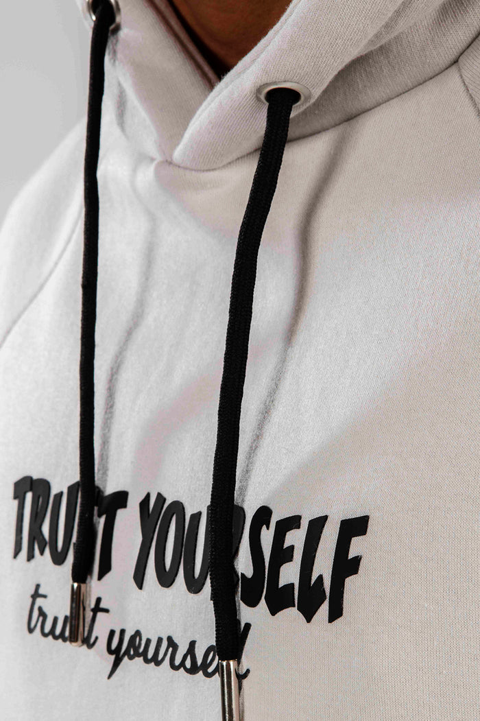 Detail of Oversized Graphic Hoodie in Carbon light grey, showing Trust Yourself streetwear print and black drawstrings.