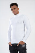 Model wearing a Tyson white turtleneck knit sweater with a slim fit, paired with dark washed denim jeans.